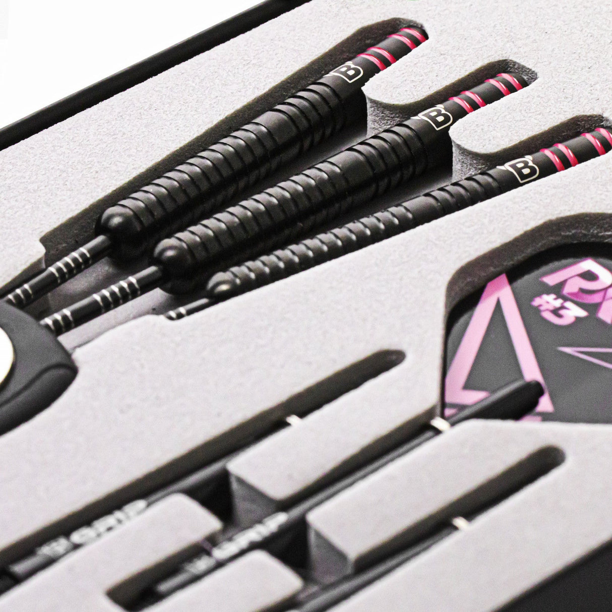 Angled close-up of three 90% tungsten darts in display case, showing grip texture and black barrels with pink ringed accents