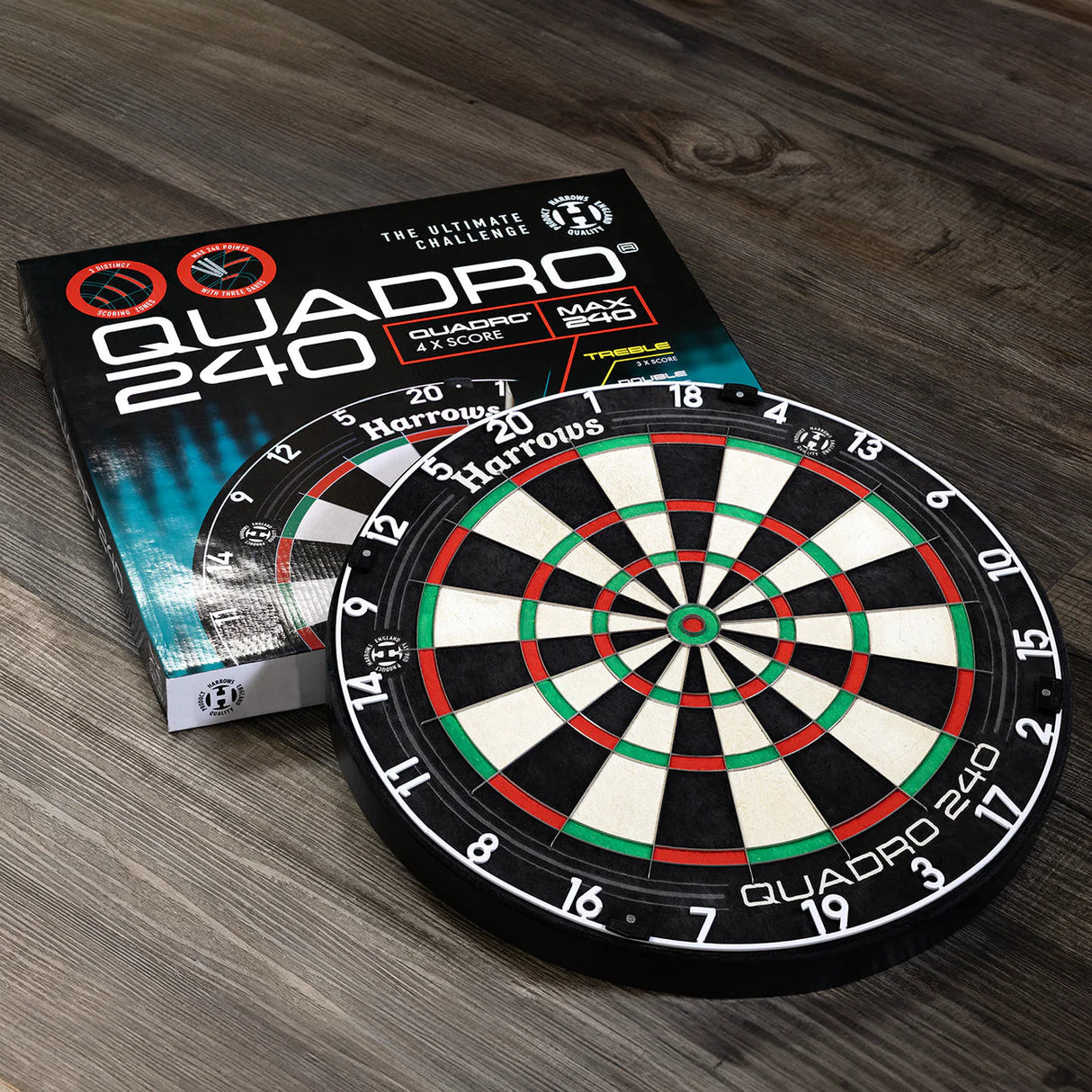 Quadro 240 dartboard with bright segment rings displayed on wood floor beside packaging, showing full product and box for darts buyers