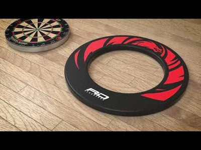 Angled view dartboard surround with red dragon design beside dartboard on wood floor, unmounted display for dart setup