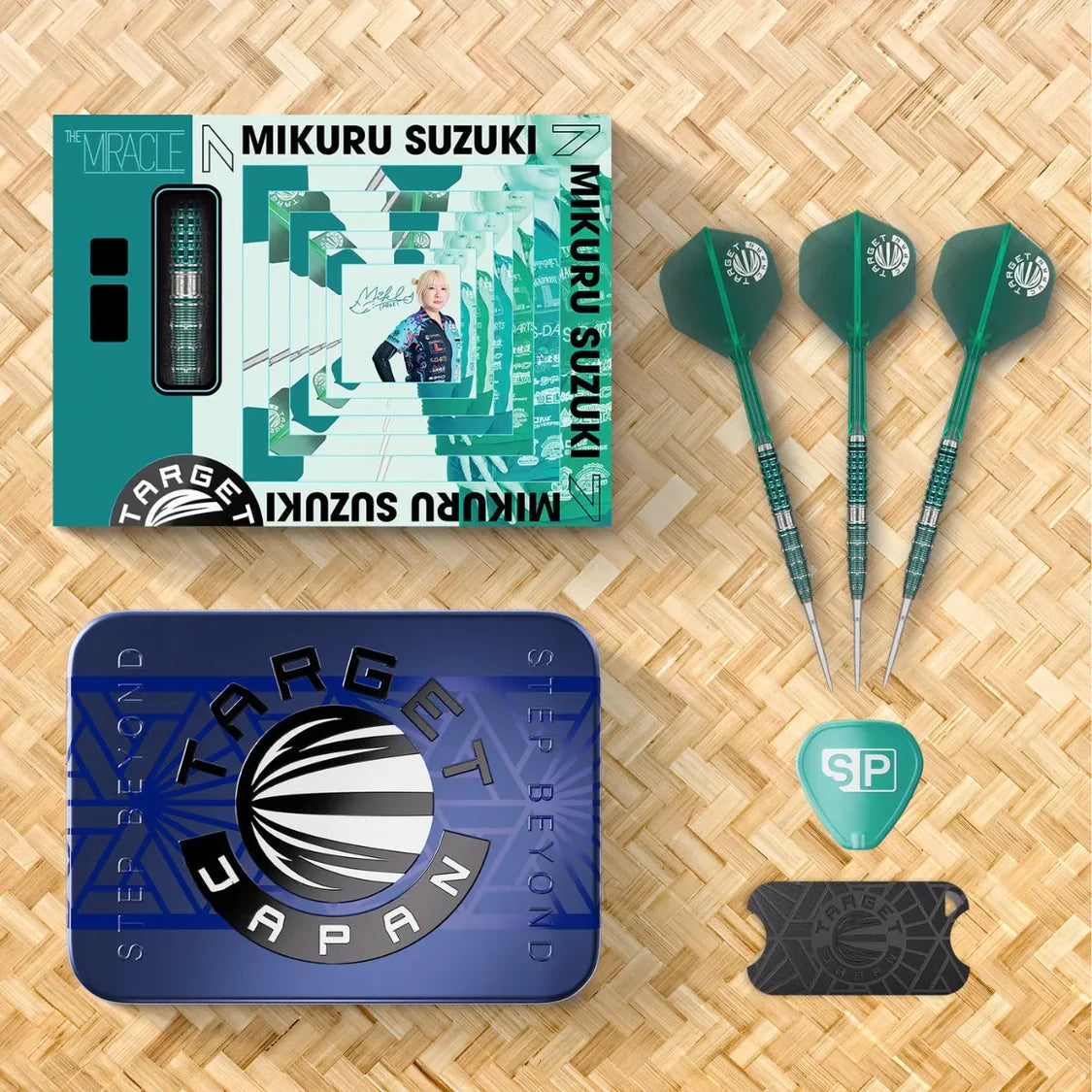 Top-down view of Mikuru Suzuki Gen 7 darts set with three tungsten darts, retail box, storage tin, flight, and dart tool on woven mat