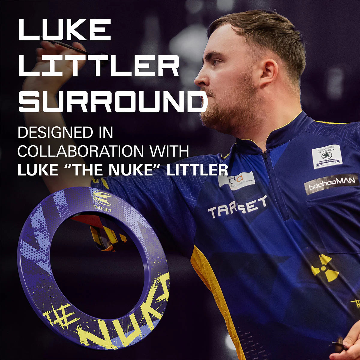 Angled lifestyle view of Luke Littler dartboard surround in purple and yellow with bold NUKE lettering, shown in front of a darts player