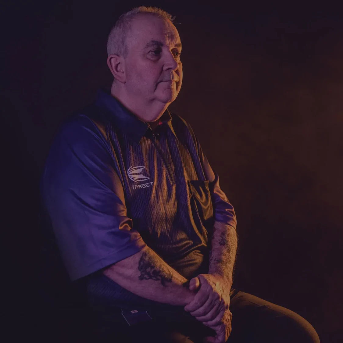 Dart shirt modeled in seated angled view, highlighting 2024 design, chest logo, and authentic player fit for darts enthusiasts