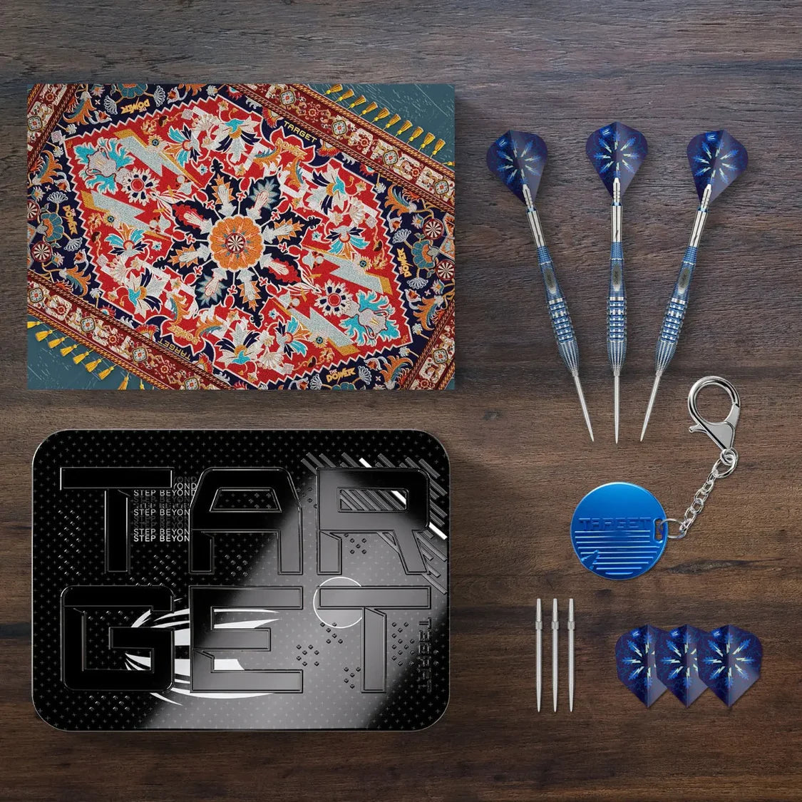 Top-down shot of Phil Taylor Gx2 darts set with three assembled darts, extra dart tips, flights, keychain, and storage case displayed.
