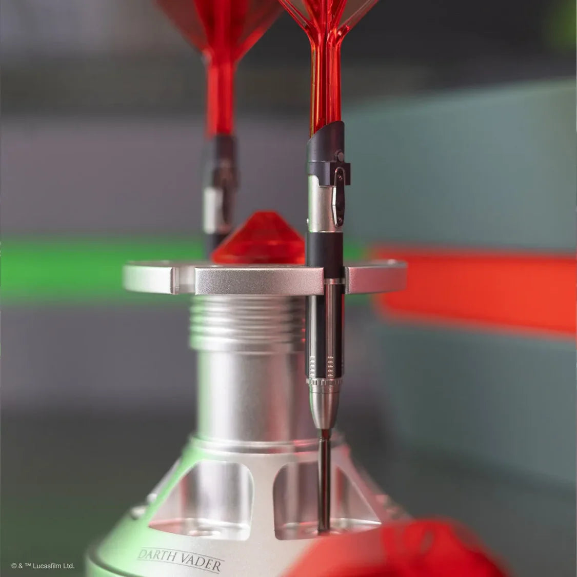 Angled close-up of limited edition tungsten darts with red flights in a display stand, showing barrel grip detail and Darth Vader laser-etched engraving