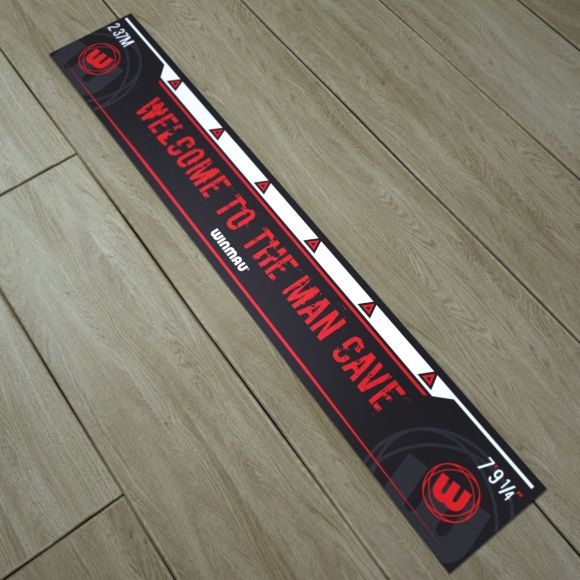 Angled top-down view of dart oche throw line mat on wood floor with measurement marks and bold 'Welcome to the Man Cave' lettering