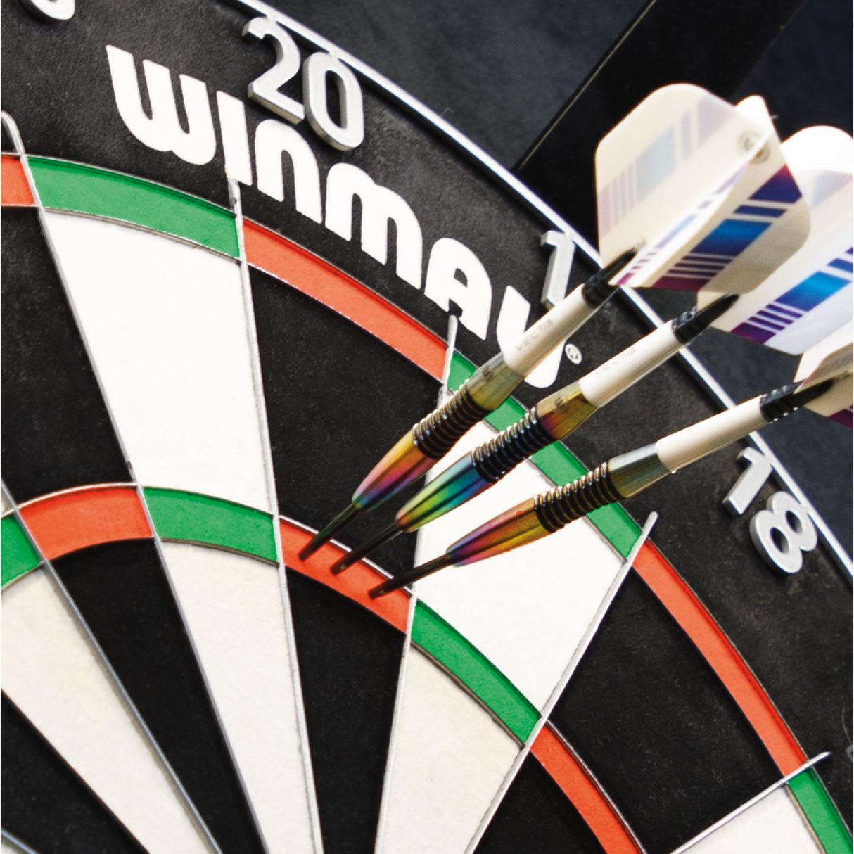 Close-up angled view of darts grouped in treble 20 segment on dartboard, highlighting steel tip barrel and flight design for precision play