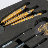 Angled close-up of three gold 90% tungsten darts with precision grooved barrels in foam case, includes flights and shafts for dart players.