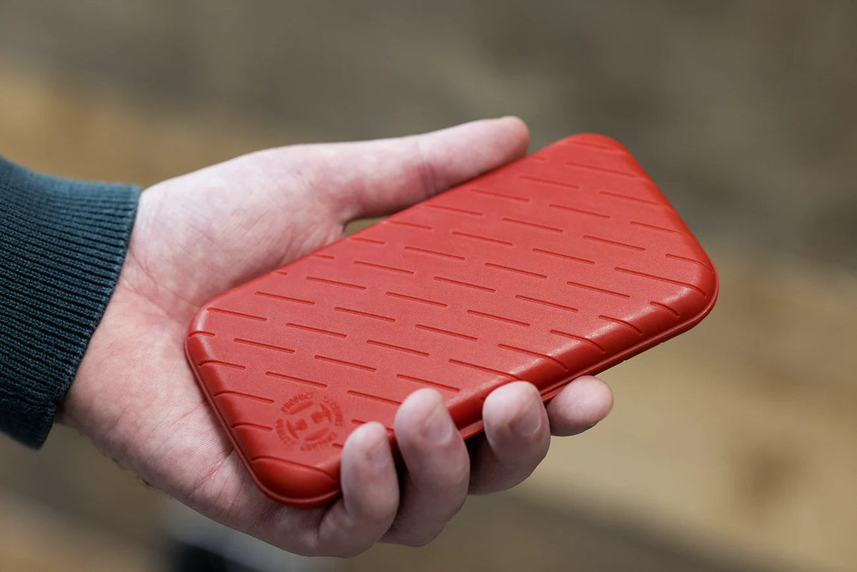 Red slim darts case with textured grip shown in hand for scale, compact dart storage accessory