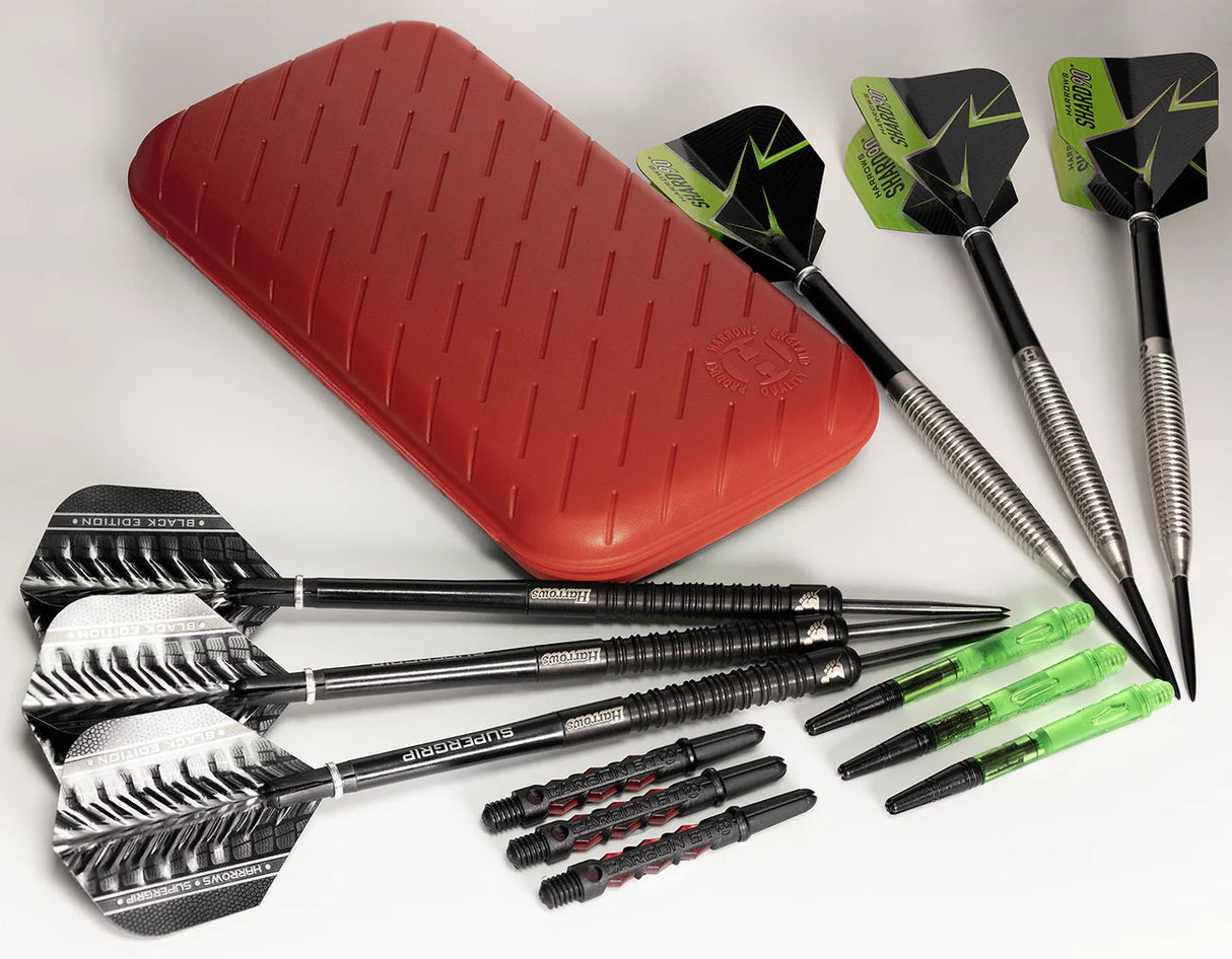 Top-down view of red slim darts case with six steel tip darts, extra shafts, and flights arranged on white background for dart players