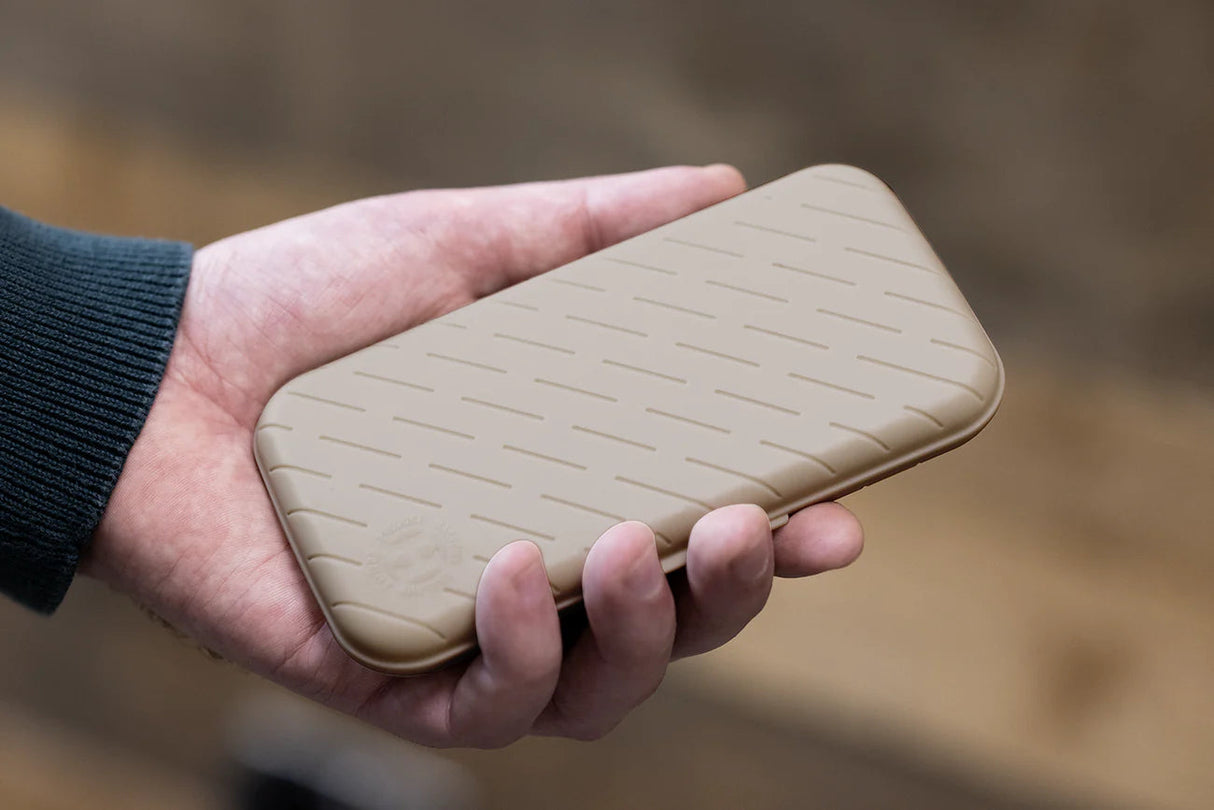Tan slim darts case with textured grip shown in hand for scale, highlighting portable storage for darts accessories.