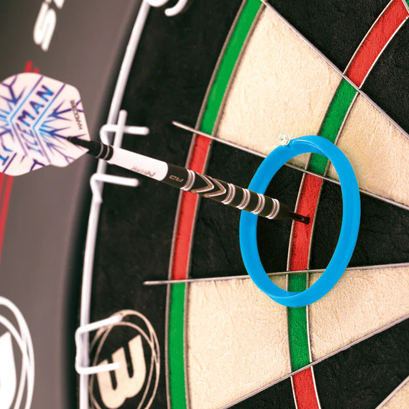 Close-up of dart embedded in dartboard treble with blue practice ring for accuracy training, showing flight and barrel grip detail