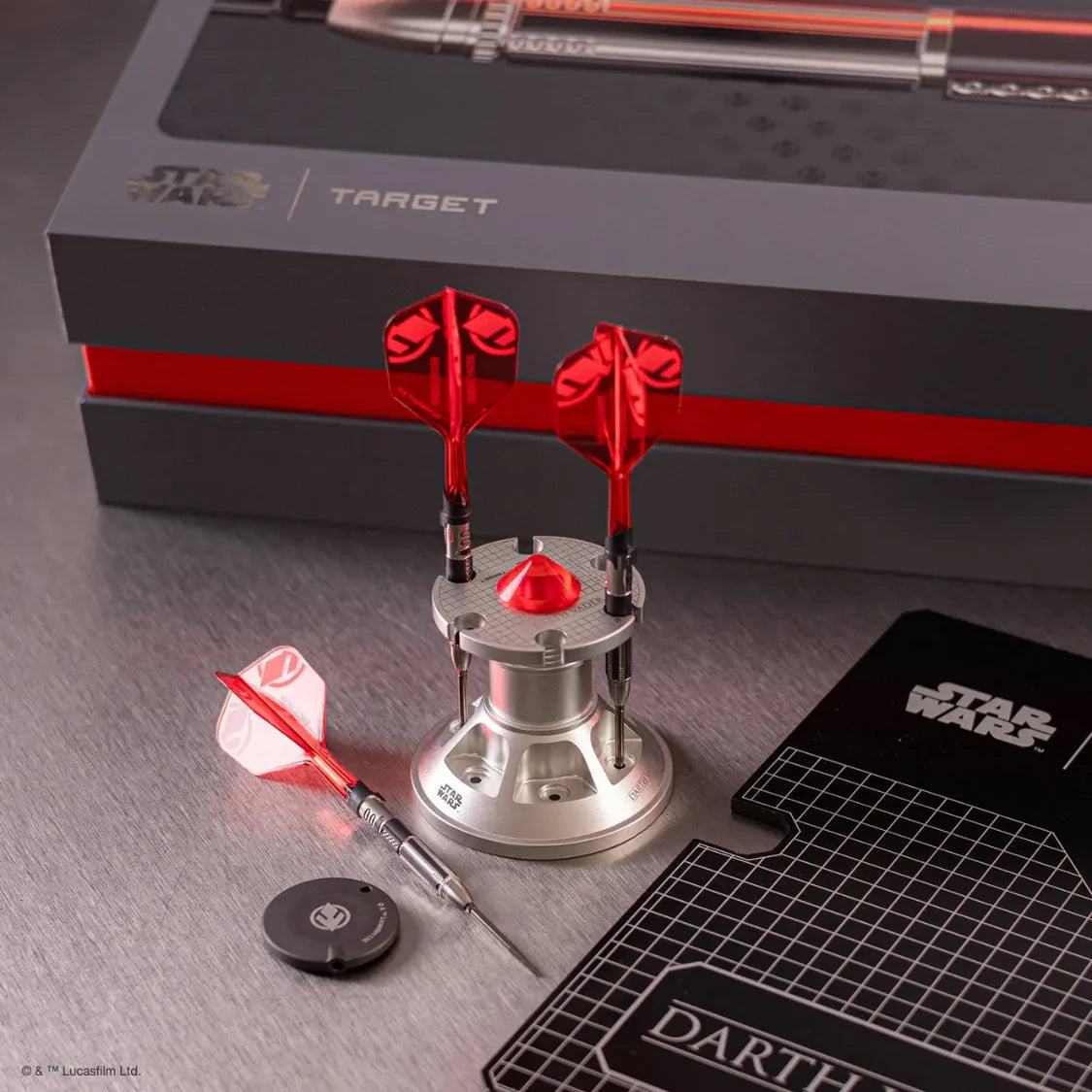 Angled close-up of Darth Vader limited edition tungsten darts in a metal stand, with red flights, one dart laid flat, accessories, and collectible packaging.