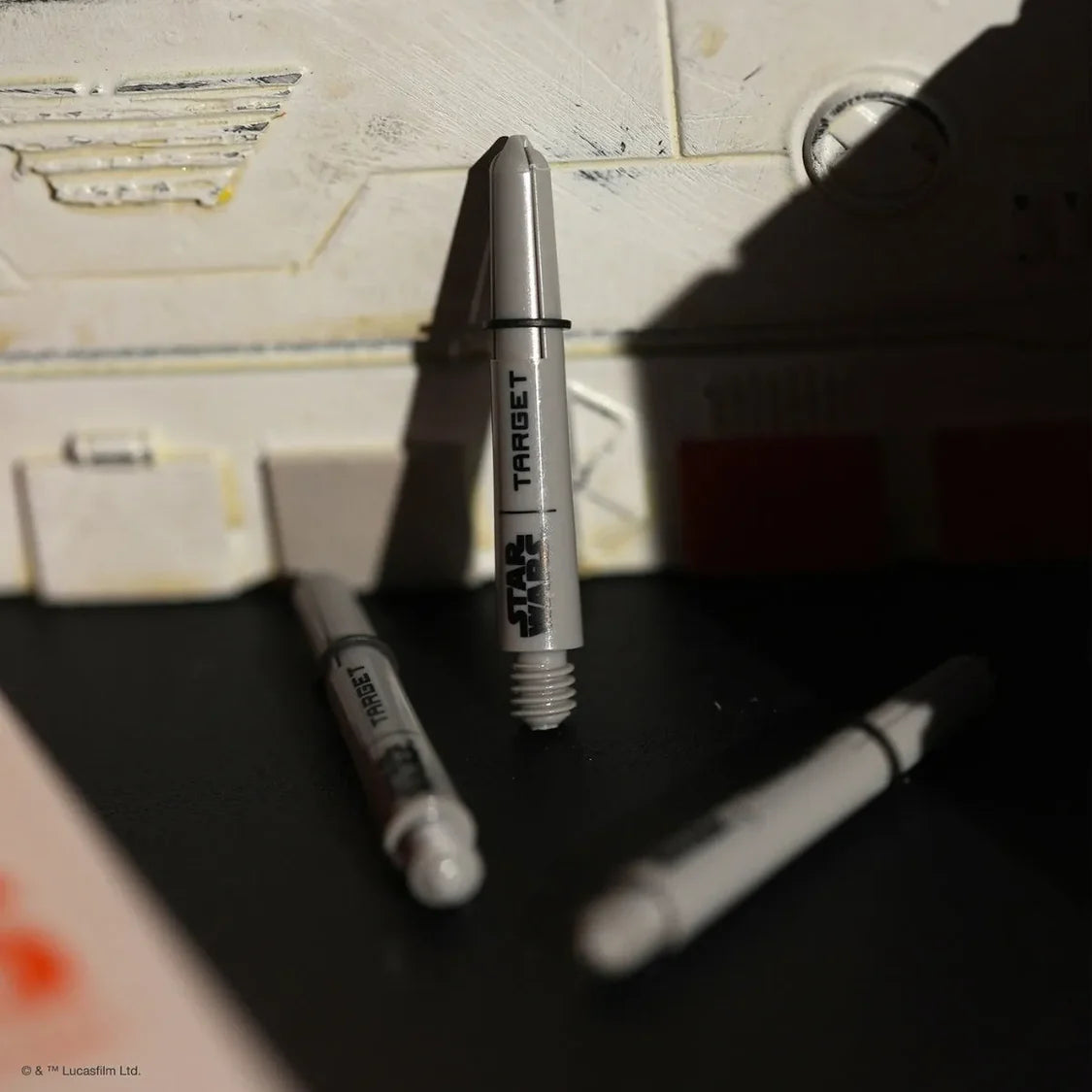Angled close-up of three Star Wars Pro Grip dart shafts on display, upright and scattered, showing threading and logo detail for dart accessories.