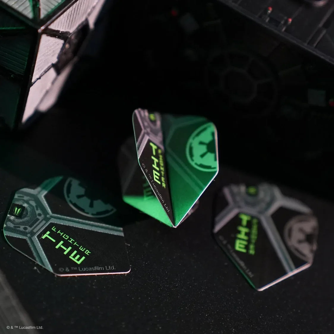 Three TIE Fighter Pro Ultra No.6 dart flights arranged on dark surface, angled view highlighting green Star Wars graphics with model TIE Fighter